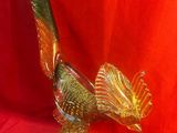 figurine d'oiseau en verre doré et vert, posée sur un tissu rouge