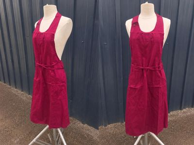 une paire de tabliers rouges posés sur des mannequins devant un mur bleu