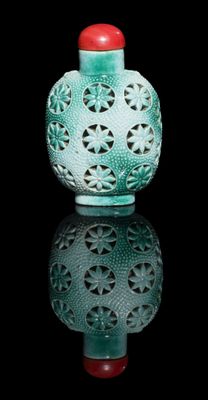 un vase vert avec un couvercle rouge posé sur une surface noire