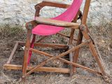 a wooden rocking chair with a pink slinger on it