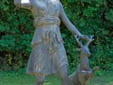 a statue of a woman and a dog in the grass