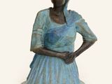 bronze statue of a woman in a blue dress with her hands on her hips