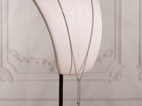 a white mannequin with a silver necklace on a black stand