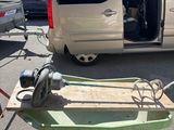 une brouette verte sur le parking, à côté d'une camionnette blanche