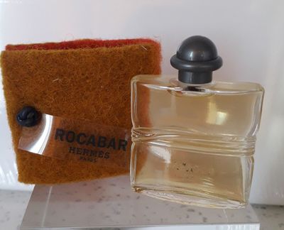 un petit flacon de parfum à côté d'un petit sac
