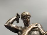 a bronze statue of a man holding a bottle of wine