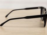 a close up of a pair of black sunglasses on a wooden table