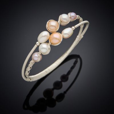 a close up of a bracelet with pearls on a black background