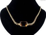 Le collier est en or et est orné d'une pierre marron.