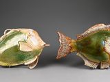 two ceramic fish sitting next to each other on a table