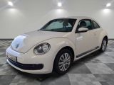 une photo d'une Coccinelle Volkswagen blanche garée sur un sol à damier