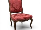 une chaise rouge dont le dossier est recouvert d'un tissu à motifs floraux et dont la structure est en bois