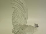 une figurine en verre représentant un oiseau posée sur une surface blanche
