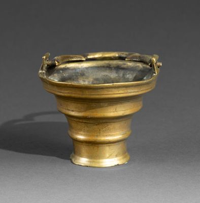 an old brass vase with a handle on a gray surface