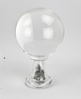 a clear glass ball with a metal base on a white surface