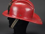 an old red fireman ' s hat on a black mannequin head