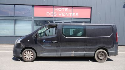 une camionnette garée devant un immeuble sur lequel est accrochée une enseigne indiquant « Hôtel des Ventes »