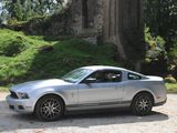 a silver mustang parked in front of a castle