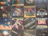 many different album covers on the wall of a room