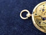 a close up of a pocket watch on a blue cloth