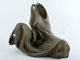 une sculpture représentant une personne assise sur une surface blanche