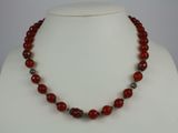 a close up of a necklace with red beads on a mannequin