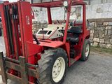 a red forklift parked in front of a stone wall