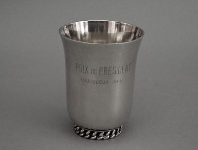 une coupe en argent posée sur une table, entourée d'une chaîne