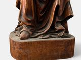 statue of a man in a robe sitting on a wooden block