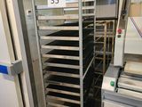une photo d'une cuisine où l'on voit une étagère métallique sur laquelle sont posés des plateaux remplis de plats