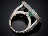 an emerald and diamond ring on a black surface