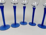 four blue wine glasses sitting on top of each other on a table
