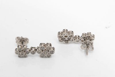 une paire de boucles d'oreilles en argent posées sur une surface blanche
