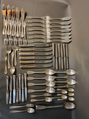 un grand nombre de cuillères et de fourchettes disposées sur une table