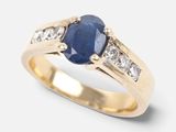 a close up of a gold ring with a sapphire and diamonds