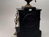 a black clock that is on a stand with a clock on top