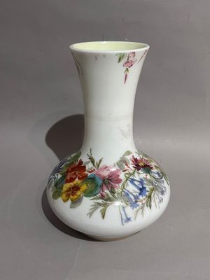 un vase blanc orné de fleurs peintes, posé sur une table