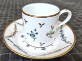 une tasse et une soucoupe blanches à bord doré posées sur une table