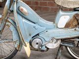 an old blue moped with a basket on the back of it