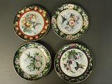 quatre assiettes ornées d'oiseaux et de fleurs, posées sur une table