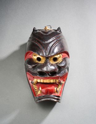 un masque accroché au mur, représentant un visage rouge et noir