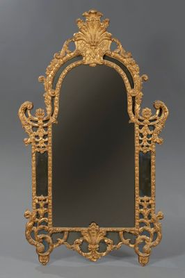 un miroir richement sculpté, avec un cadre doré sur fond gris