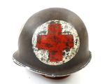 an old helmet with a red cross painted on it on a white surface