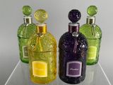 three different colored bottles sitting on a clear shelf
