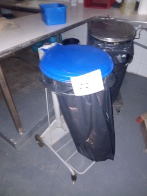 une poubelle bleue posée sur un support métallique