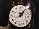 a clock that is under a glass dome on a table