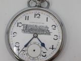 a silver pocket watch with a train drawing on it