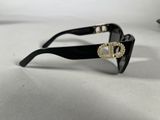 black sunglasses with a gold buckle on the front of them