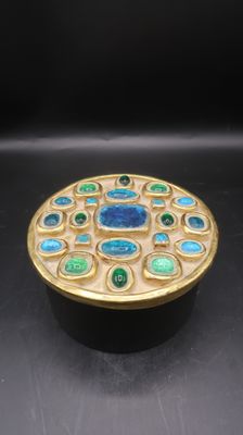a close up of a gold and green box on a black surface