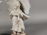 pair of white porcelain figurines of children with umbrellas